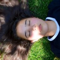 Young woman laying on the glass with her eyes closed and long hair
