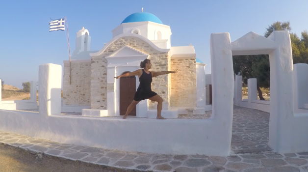 Woman in a warrior pose on a church wall in Greek Islands