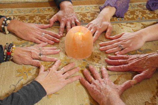 Gentle Heart Yoga and Wellness studio with women's hands in a circle around a candle after completing Women's Yoga Circle