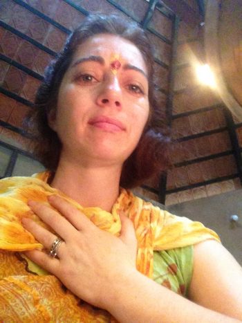 Yulia at Vaidyagrama inside a temple with a hand on her chest